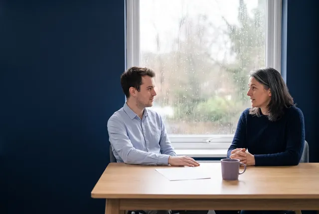 Owner and colleague reviewing a one page cloud disaster recovery plan at a window table in a small UK office