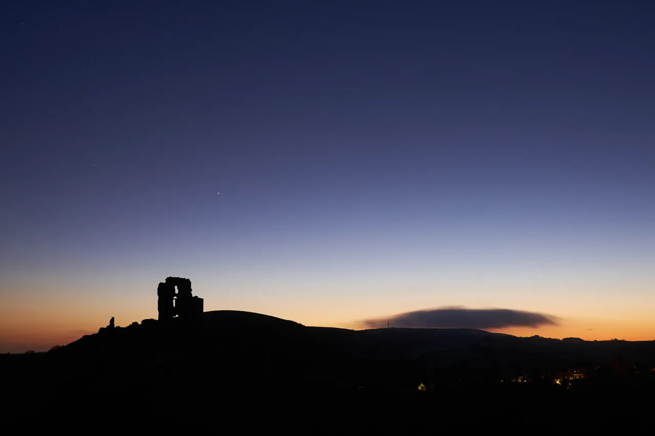 Corfe Castle silhouetted at dusk on the Isle of Purbeck near Swanage, Dorset