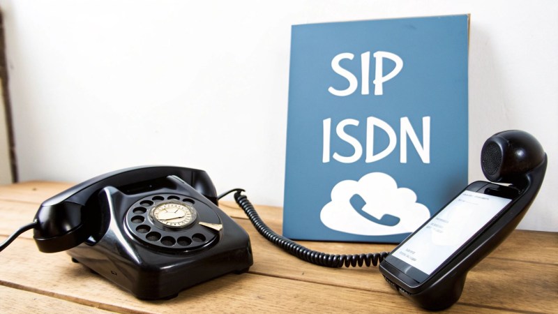 Classic rotary telephone and smartphone with SIP ISDN cloud telephony sign on wooden desk